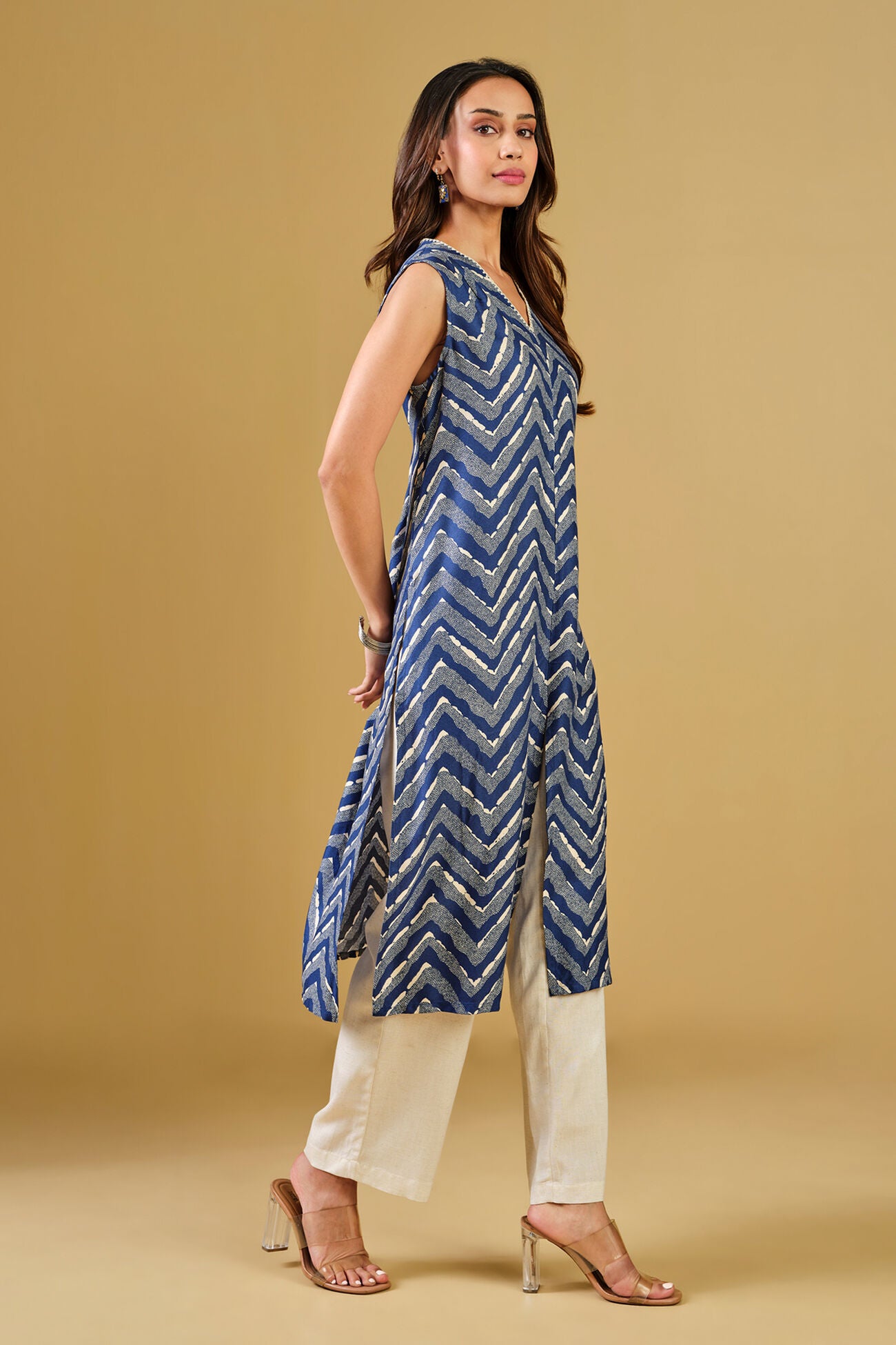 Woman wearing a blue zigzag patterned kurta with beige pants on a beige background