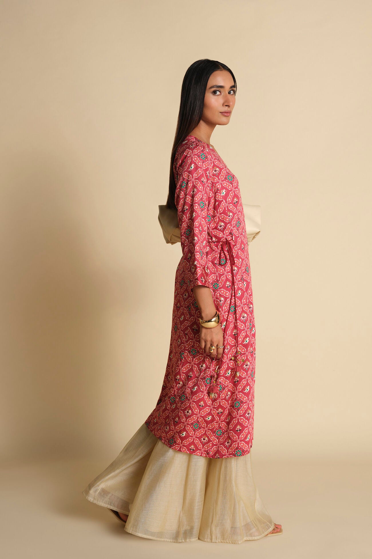 Woman wearing a pink floral kurta with a beige background