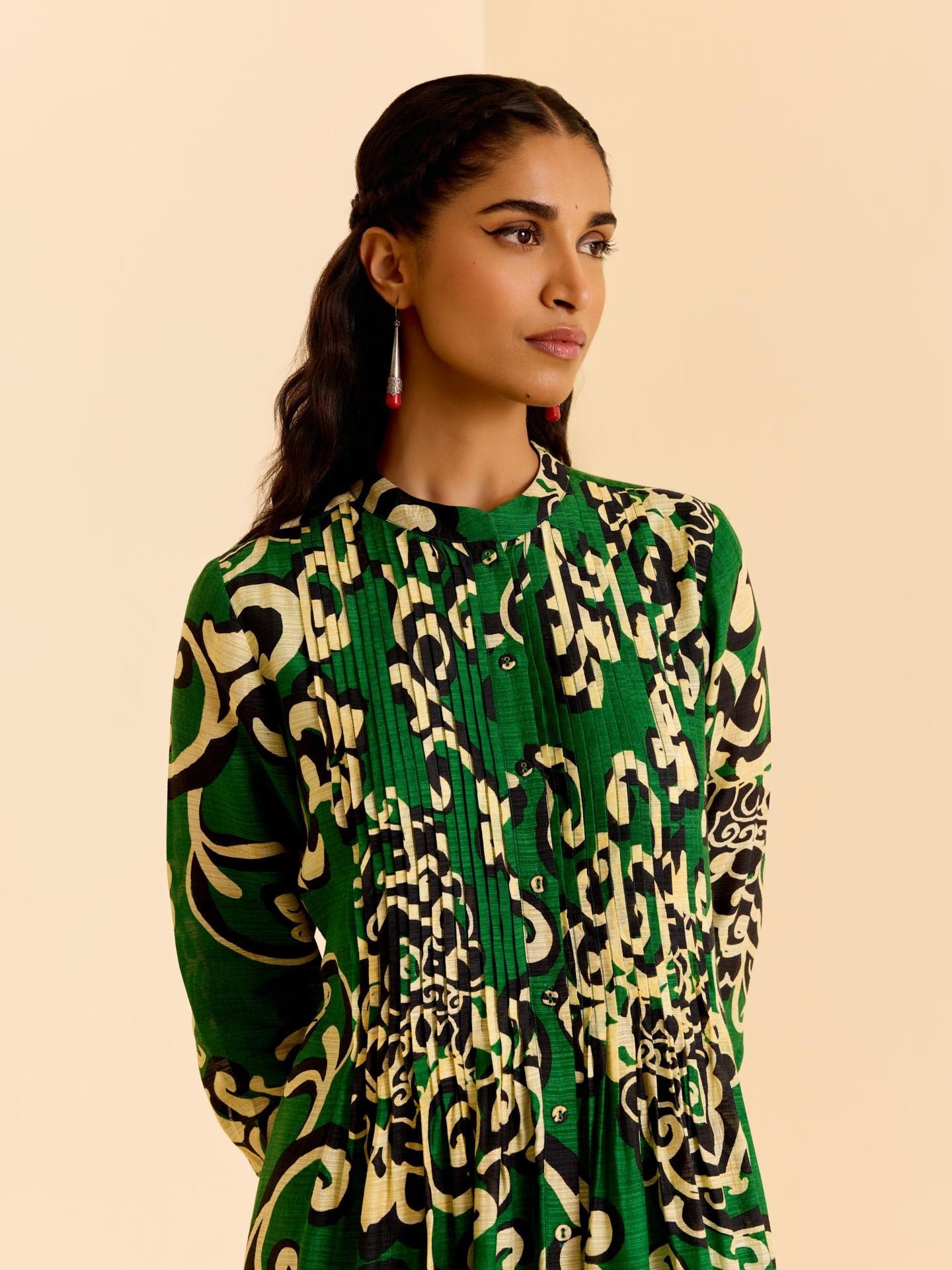 Woman wearing a green patterned dress against a beige background