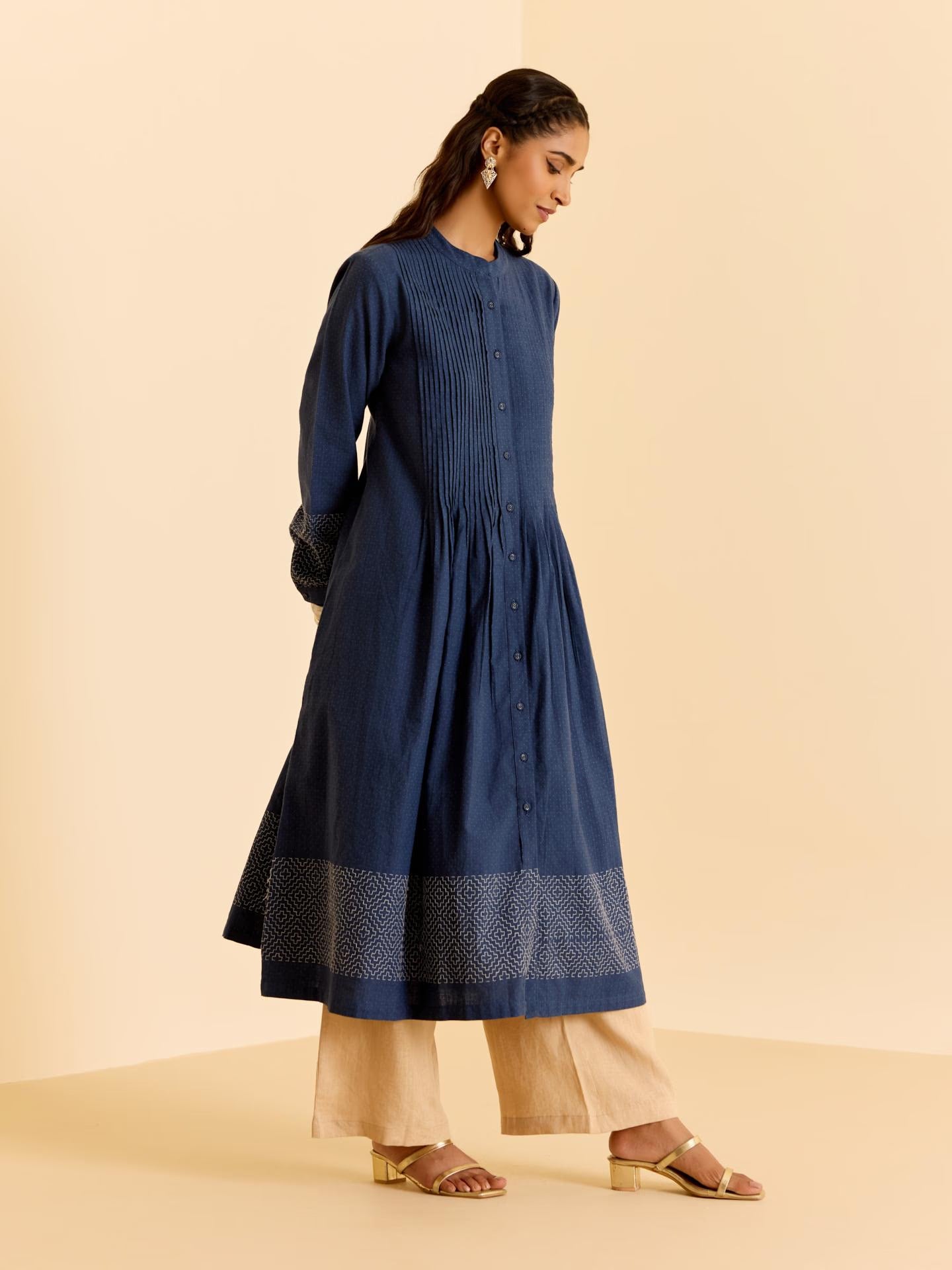 Woman wearing a blue dress with beige pants on a beige background