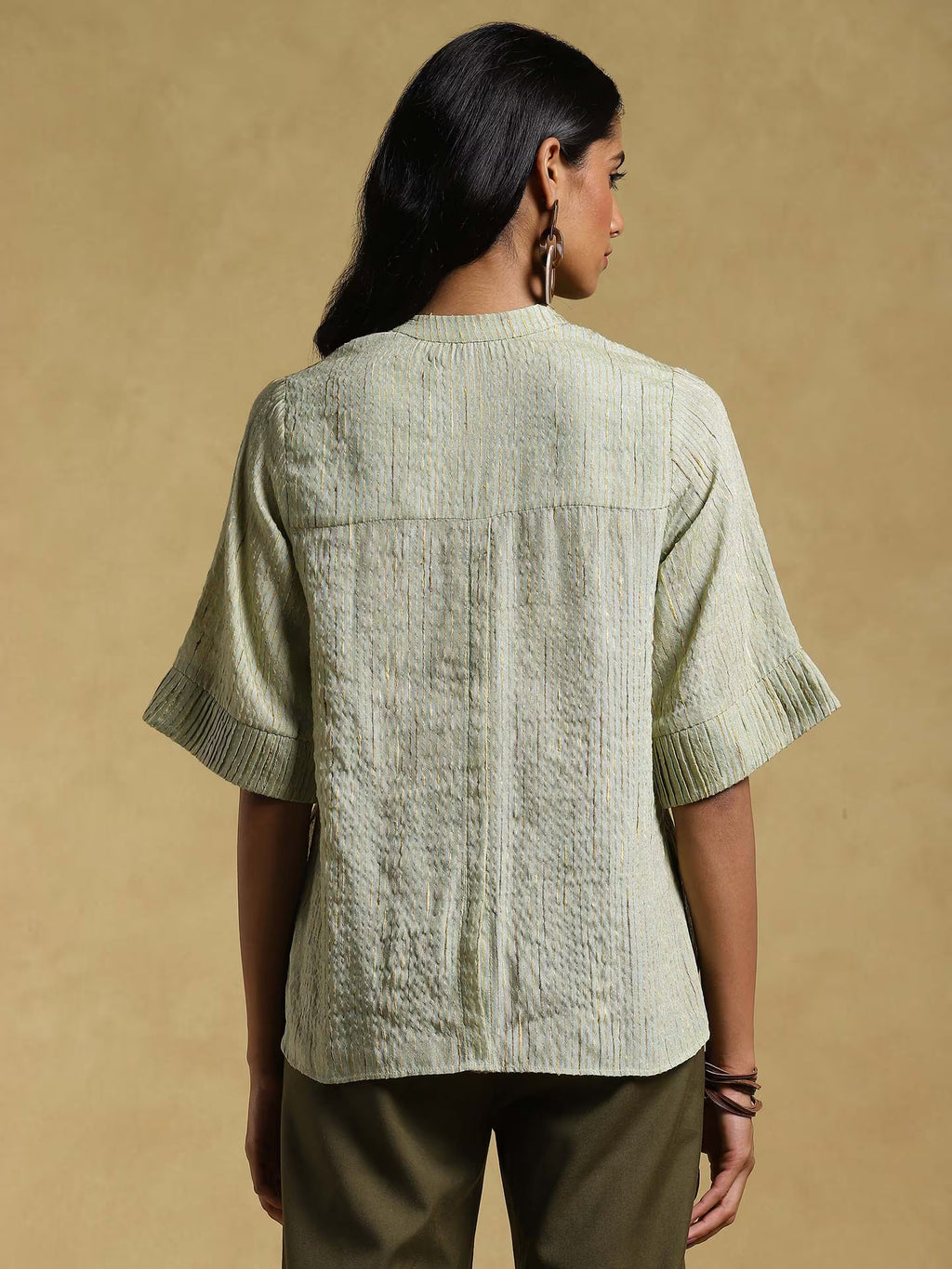 Woman wearing a textured light green shirt against a beige background
