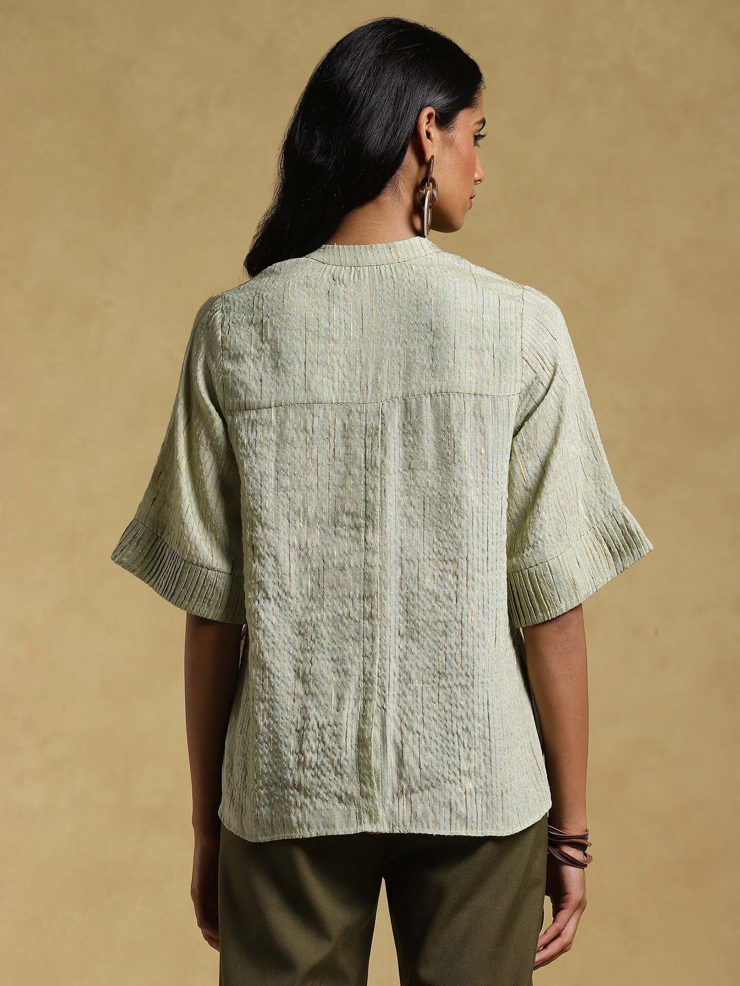 Woman wearing a textured light green shirt against a beige background