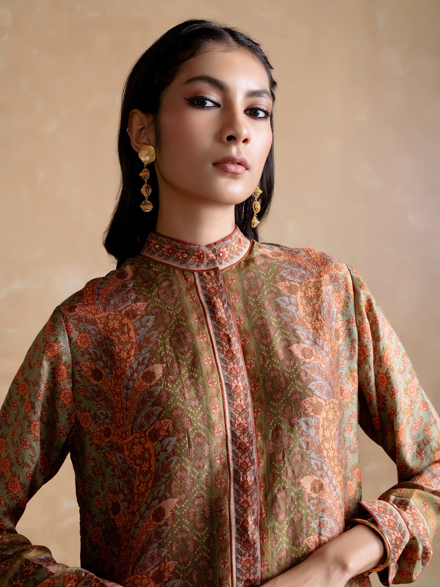 Woman wearing a patterned traditional outfit against a beige background