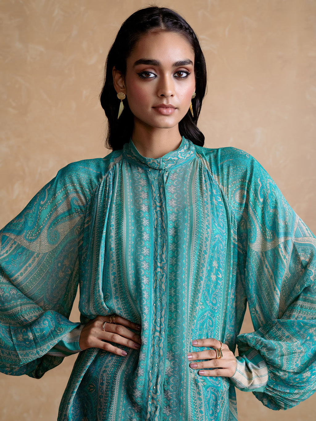 Woman wearing a Blue patterned outfit against a beige background