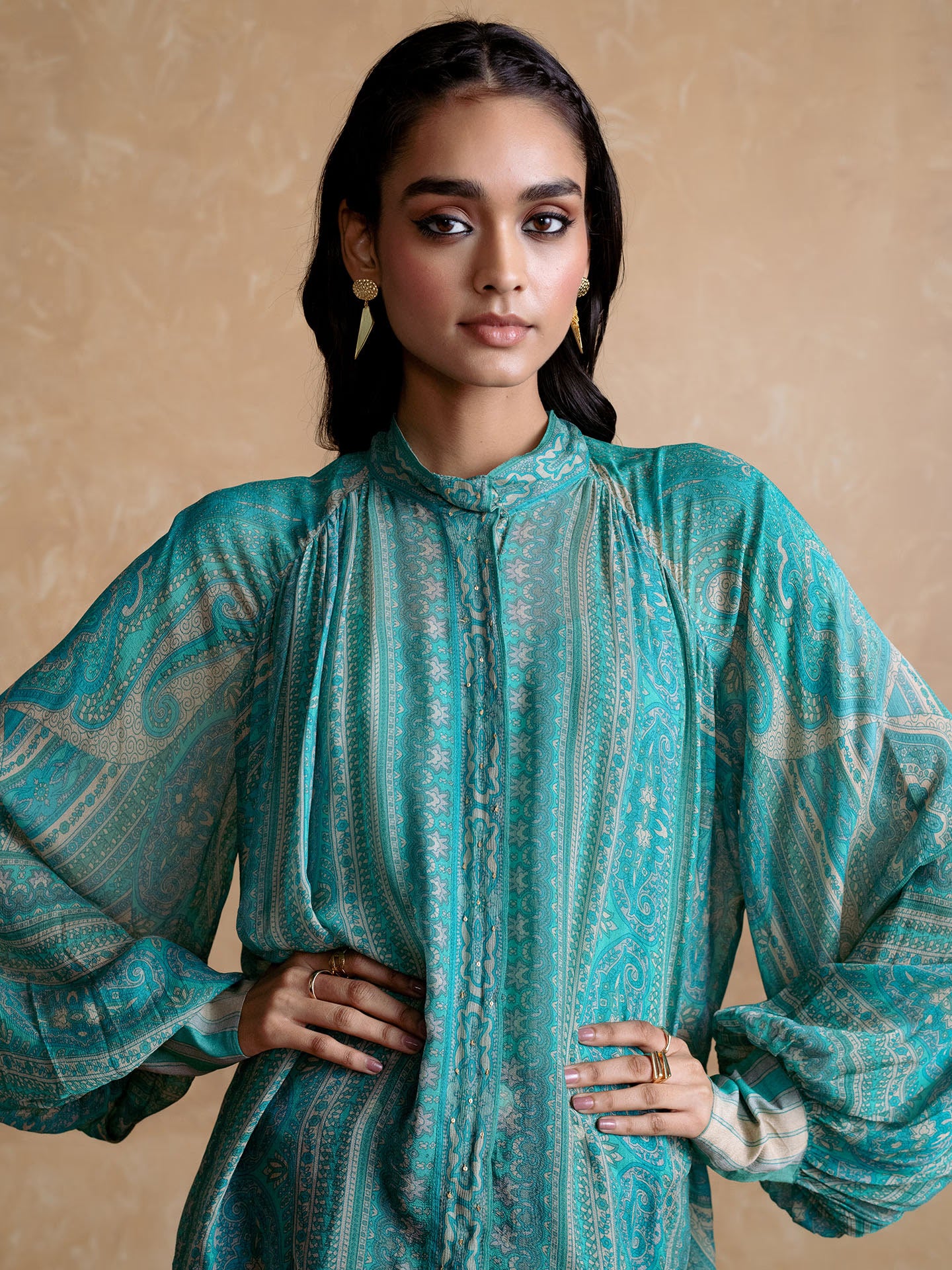 Woman wearing a Blue patterned outfit against a beige background