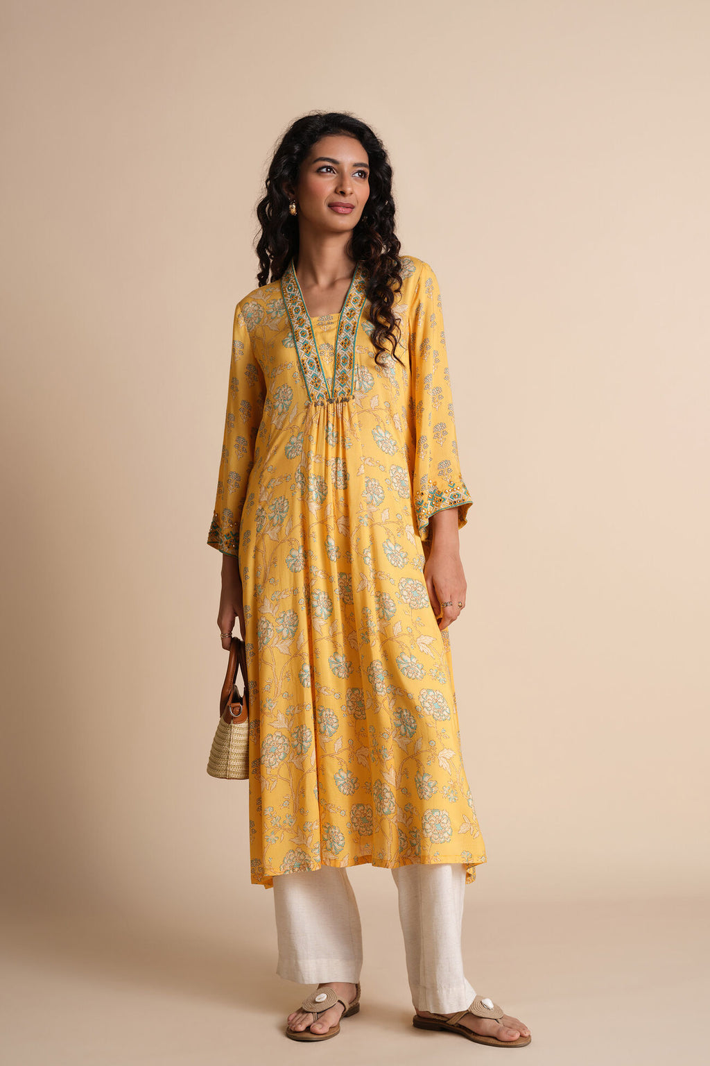Woman wearing a yellow kurta with white pants on a beige background