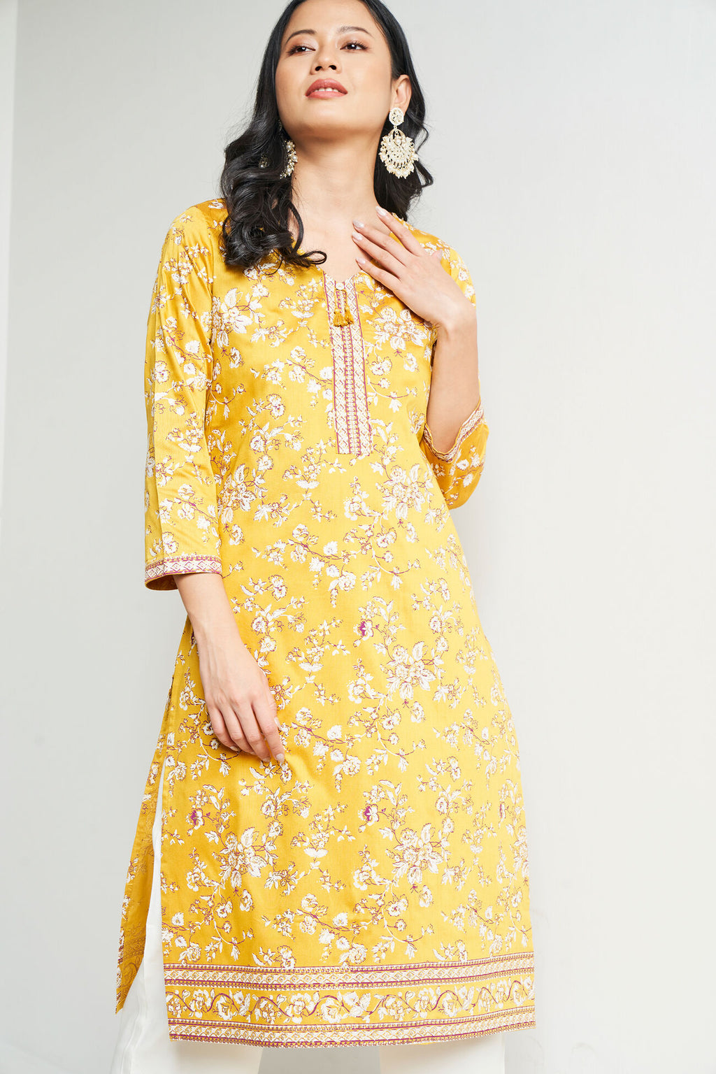 Woman wearing a yellow floral dress against a white background