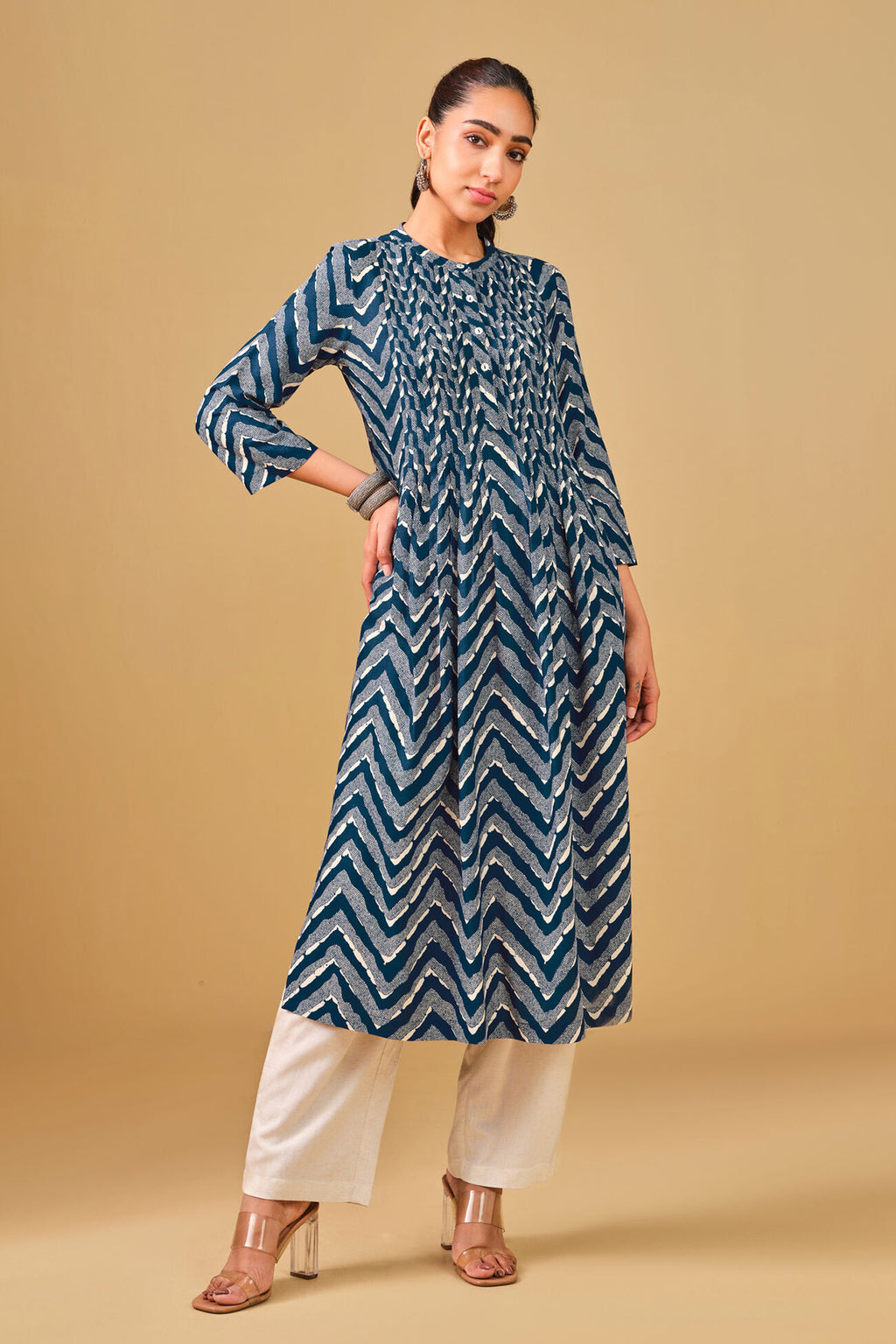 Woman wearing a blue and white patterned kurta with white pants on a beige background