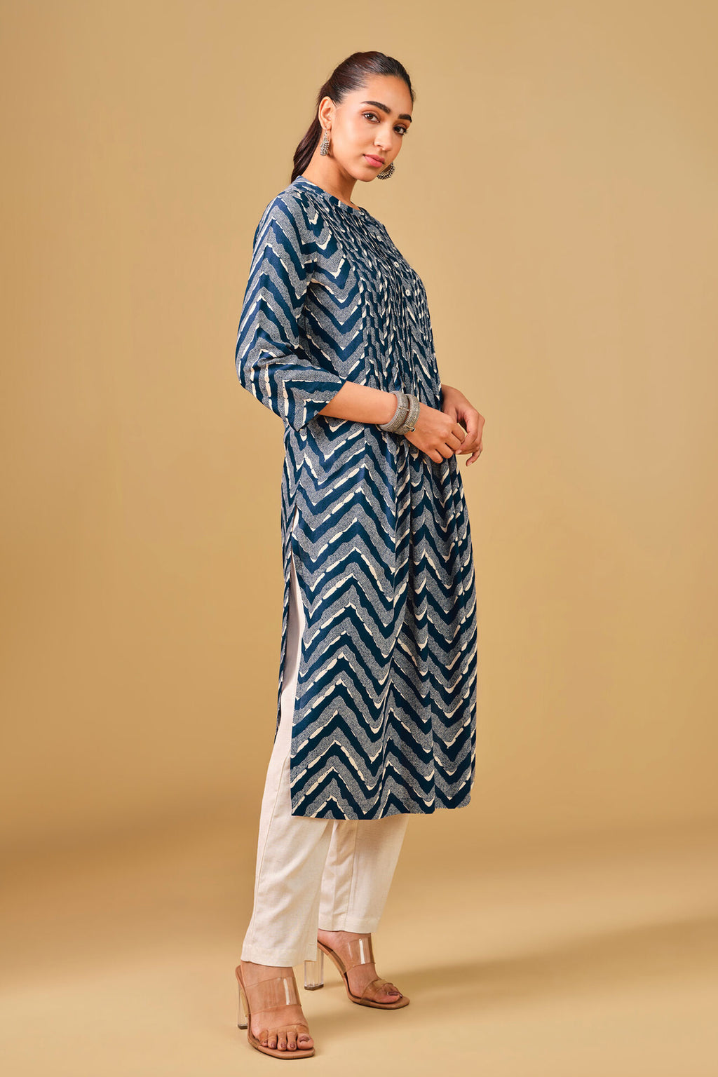 Woman wearing a blue patterned kurta with white pants on a beige background