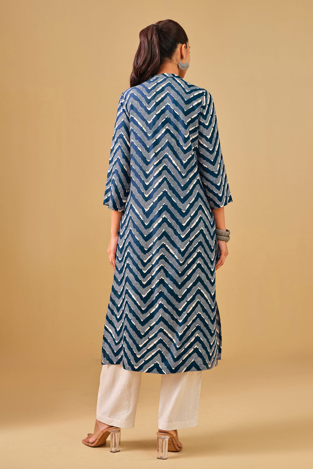 Woman wearing a blue and white patterned kurta with white pants on a beige background