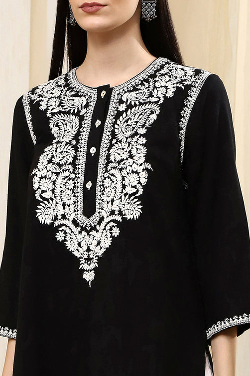Black outfit with white embroidery on a neutral background
