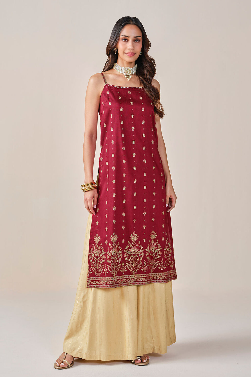 Woman wearing a red and gold traditional outfit on a beige background