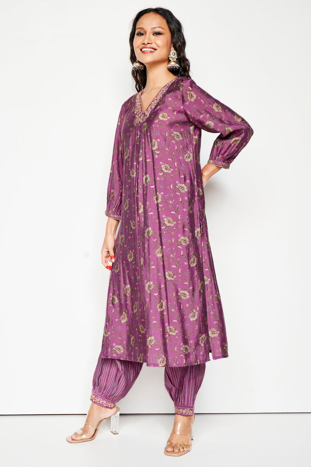 Woman wearing a purple patterned kurta with matching pants on a white background