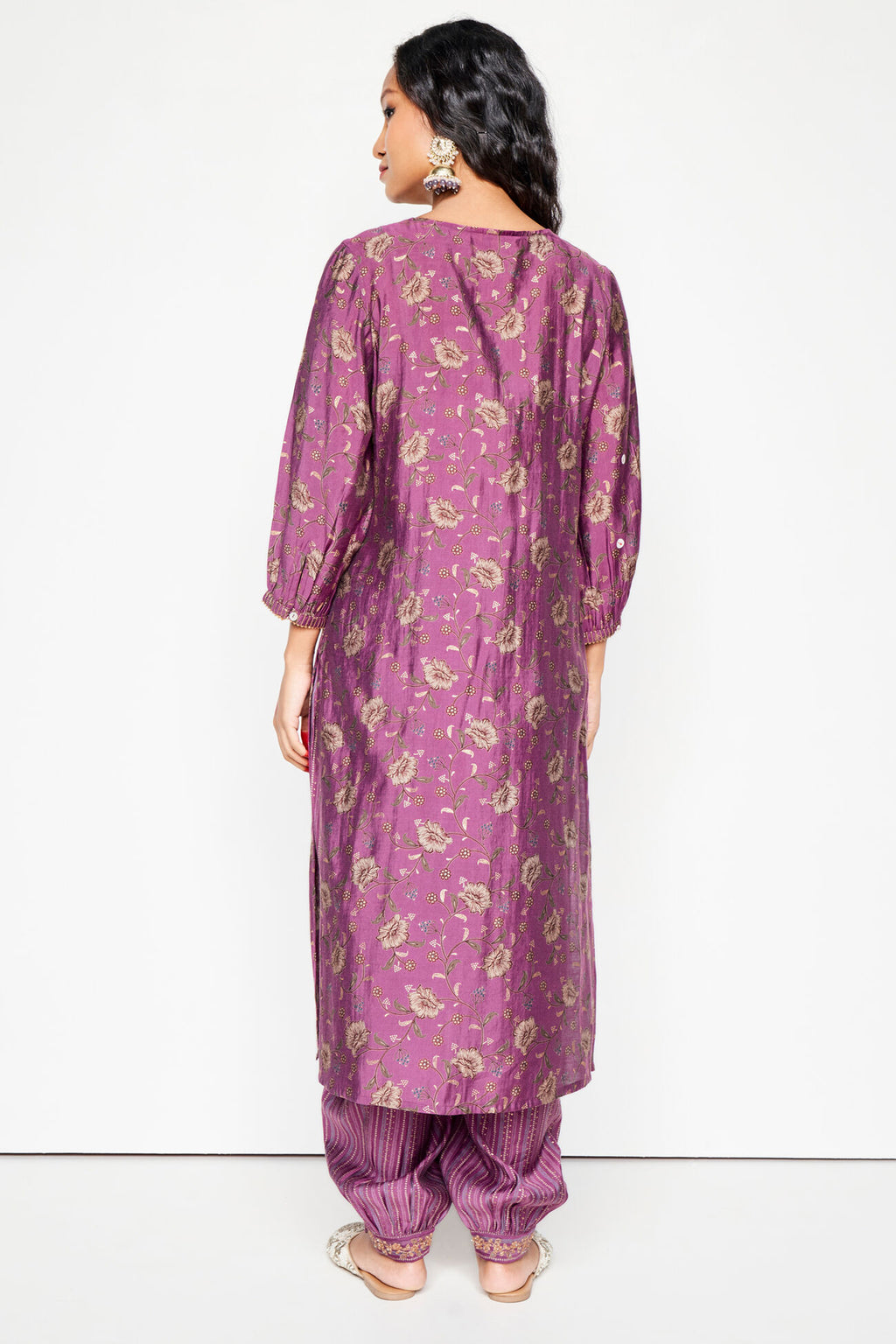 Woman wearing a purple floral kurta with matching pants on a white background
