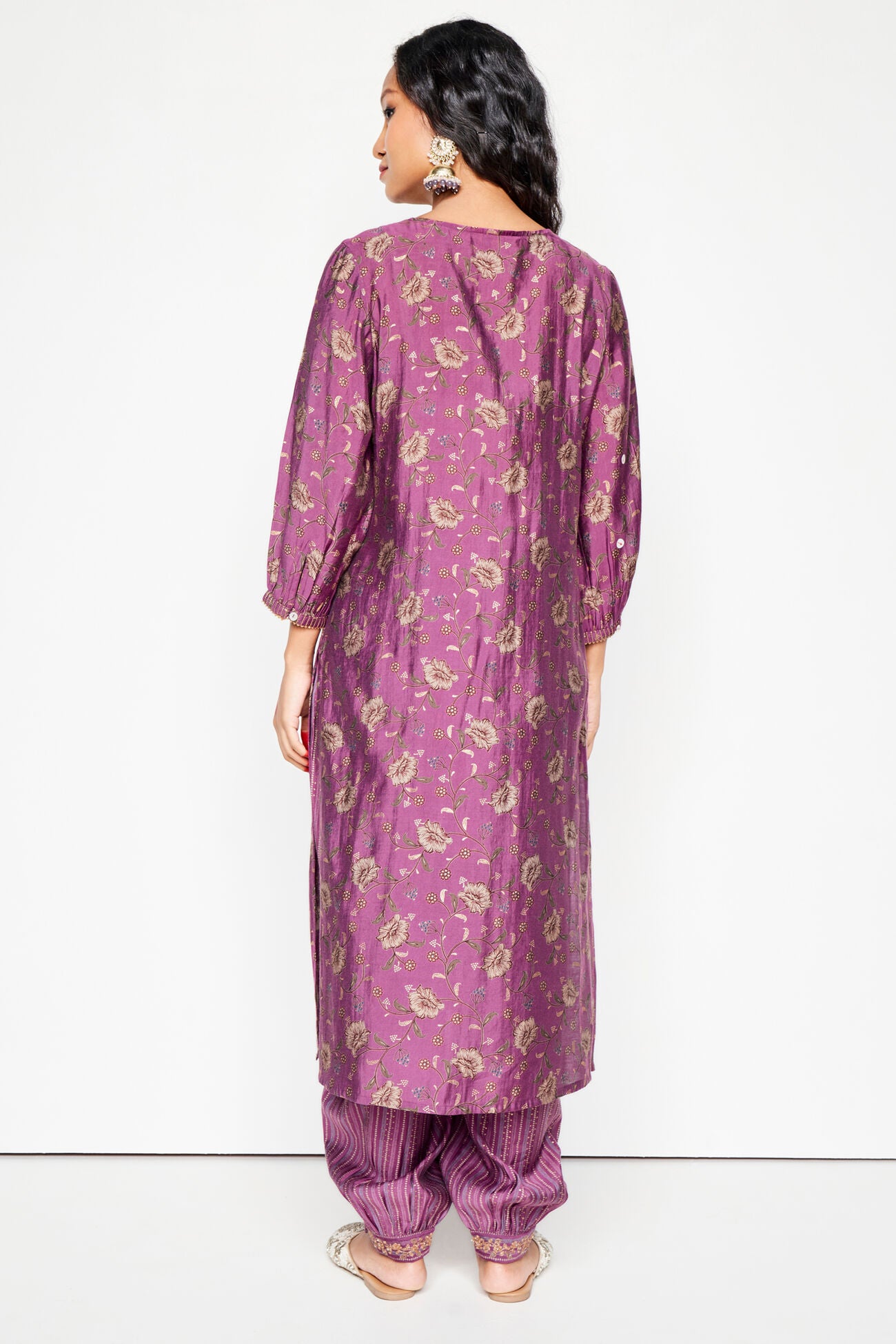 Woman wearing a purple floral kurta with matching pants on a white background