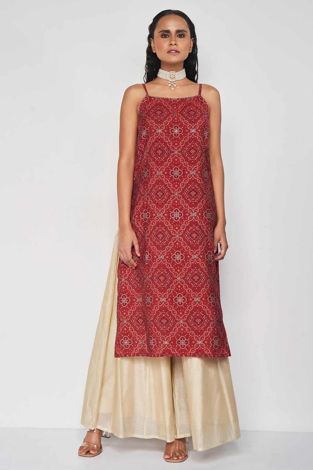 Woman wearing a red patterned top and beige skirt 