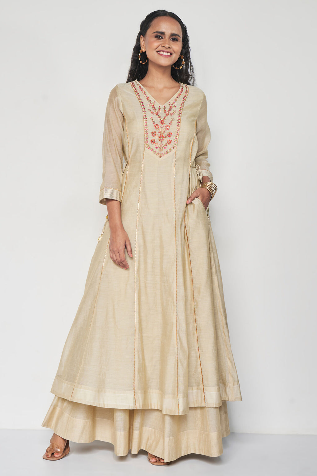 Woman wearing a beige embroidered dress on a white background