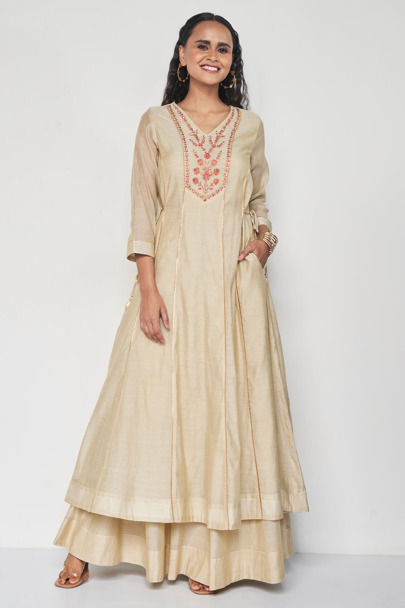 Woman wearing a beige embroidered dress on a white background