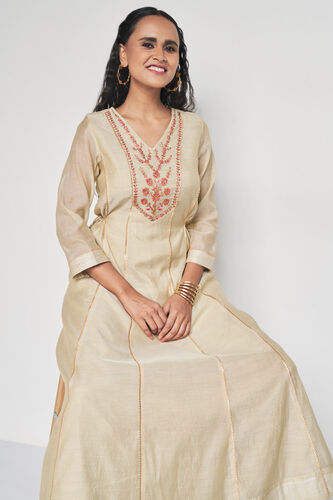 Woman wearing a beige embroidered traditional outfit on a white background