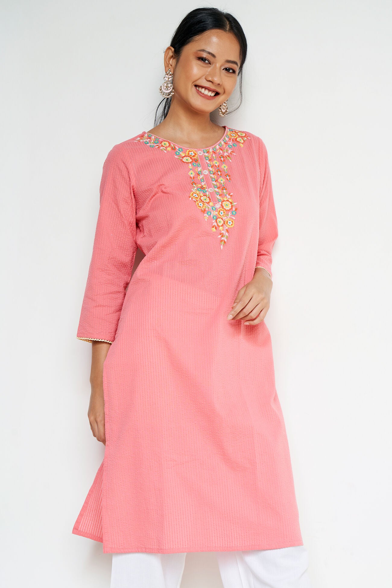 Woman wearing a pink kurta with floral embroidery on a white background