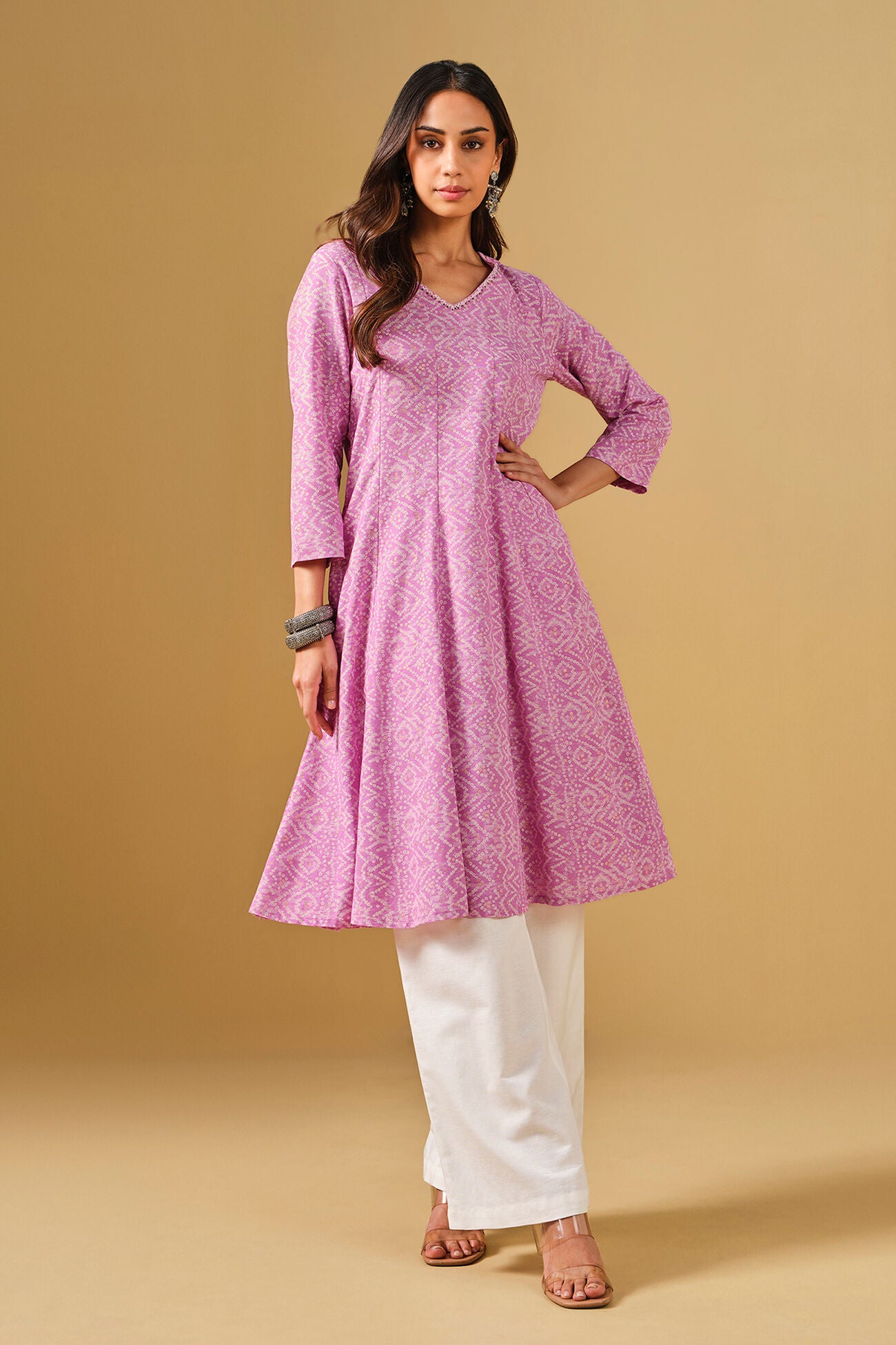 Woman wearing a pink kurta with white pants on a beige background