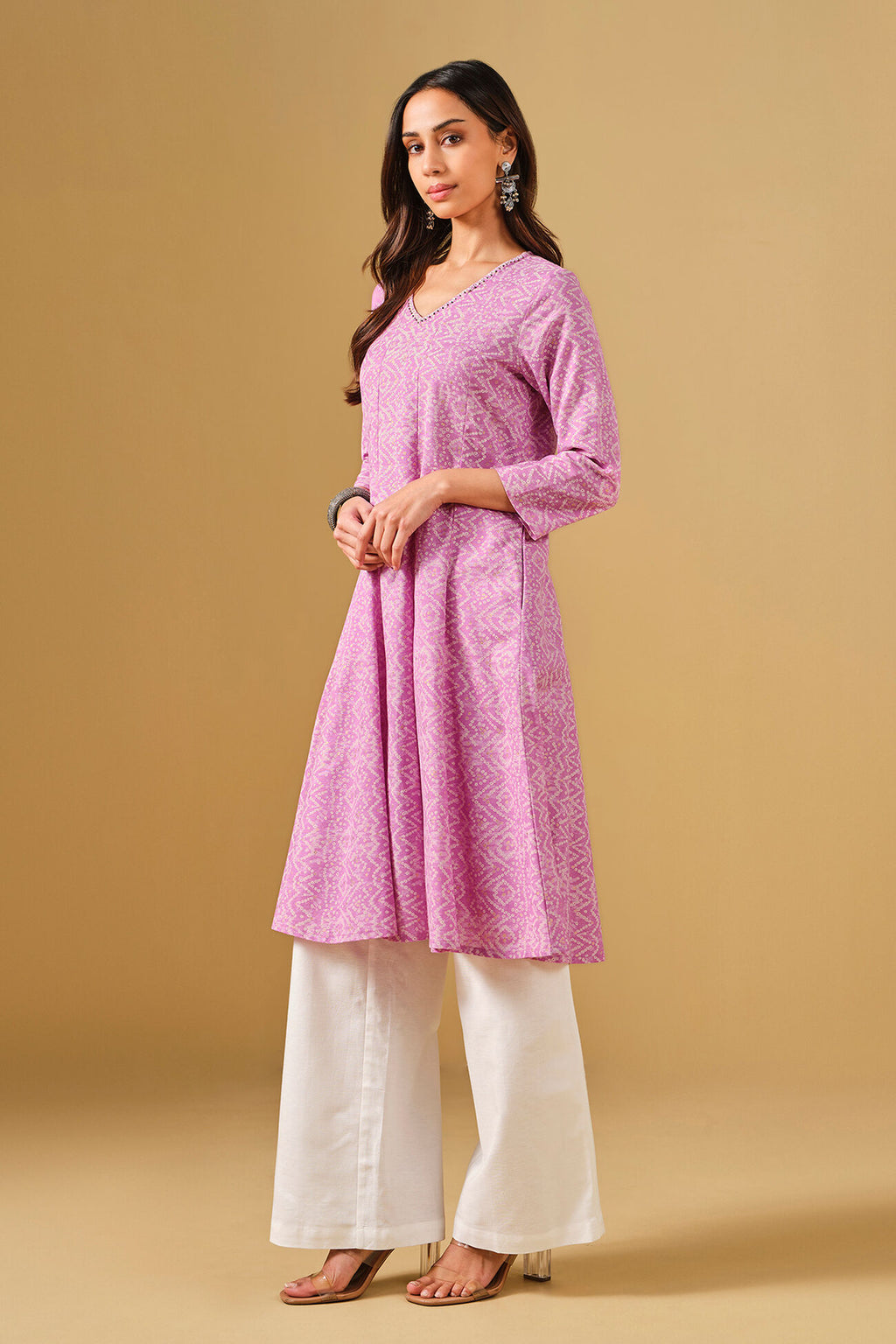 Woman wearing a pink kurta with white pants on a beige background