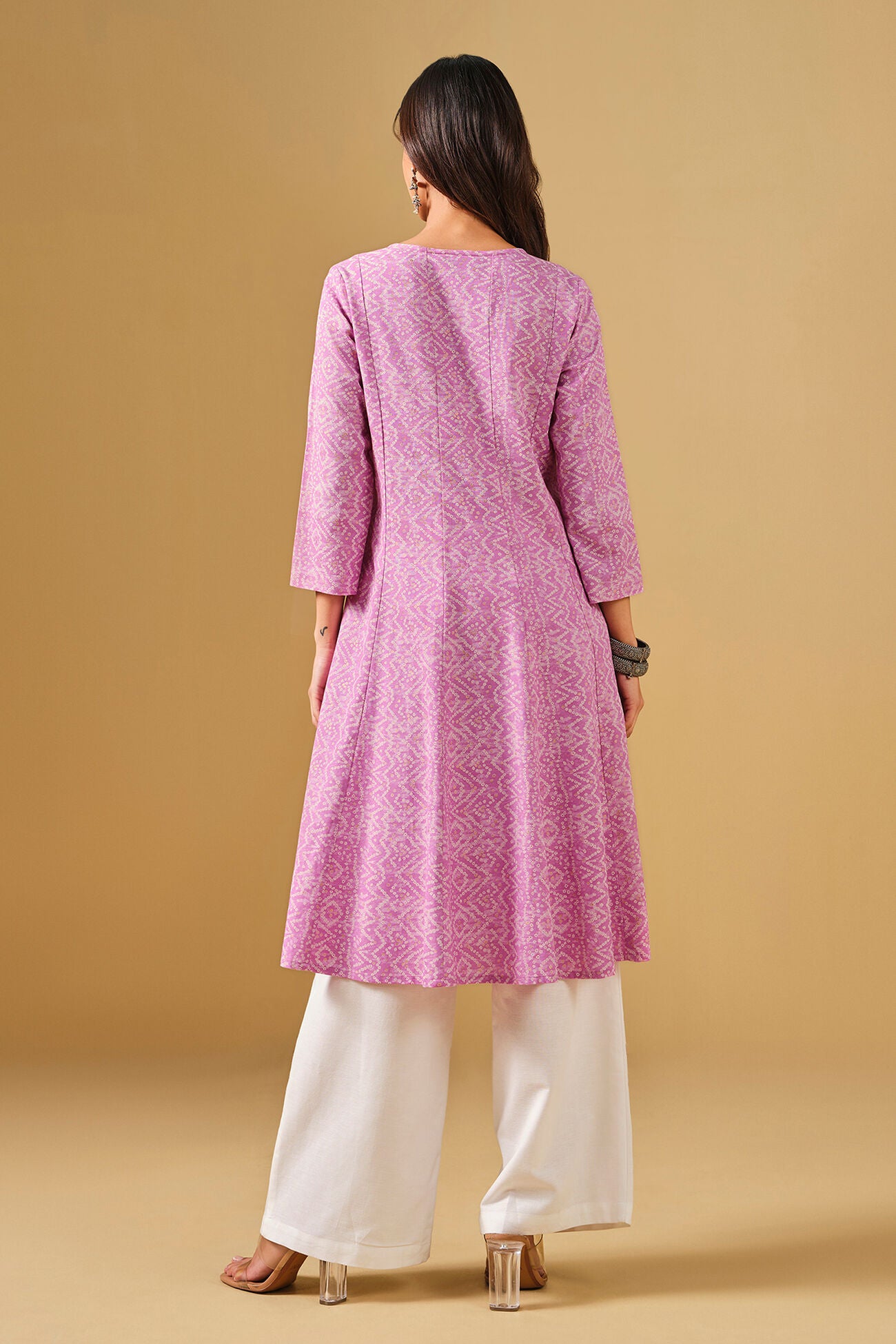 Woman wearing a pink kurta with white pants on a beige background