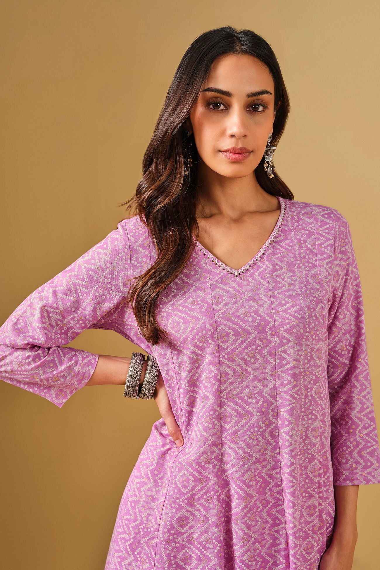 Woman wearing a pink patterned dress against a beige background