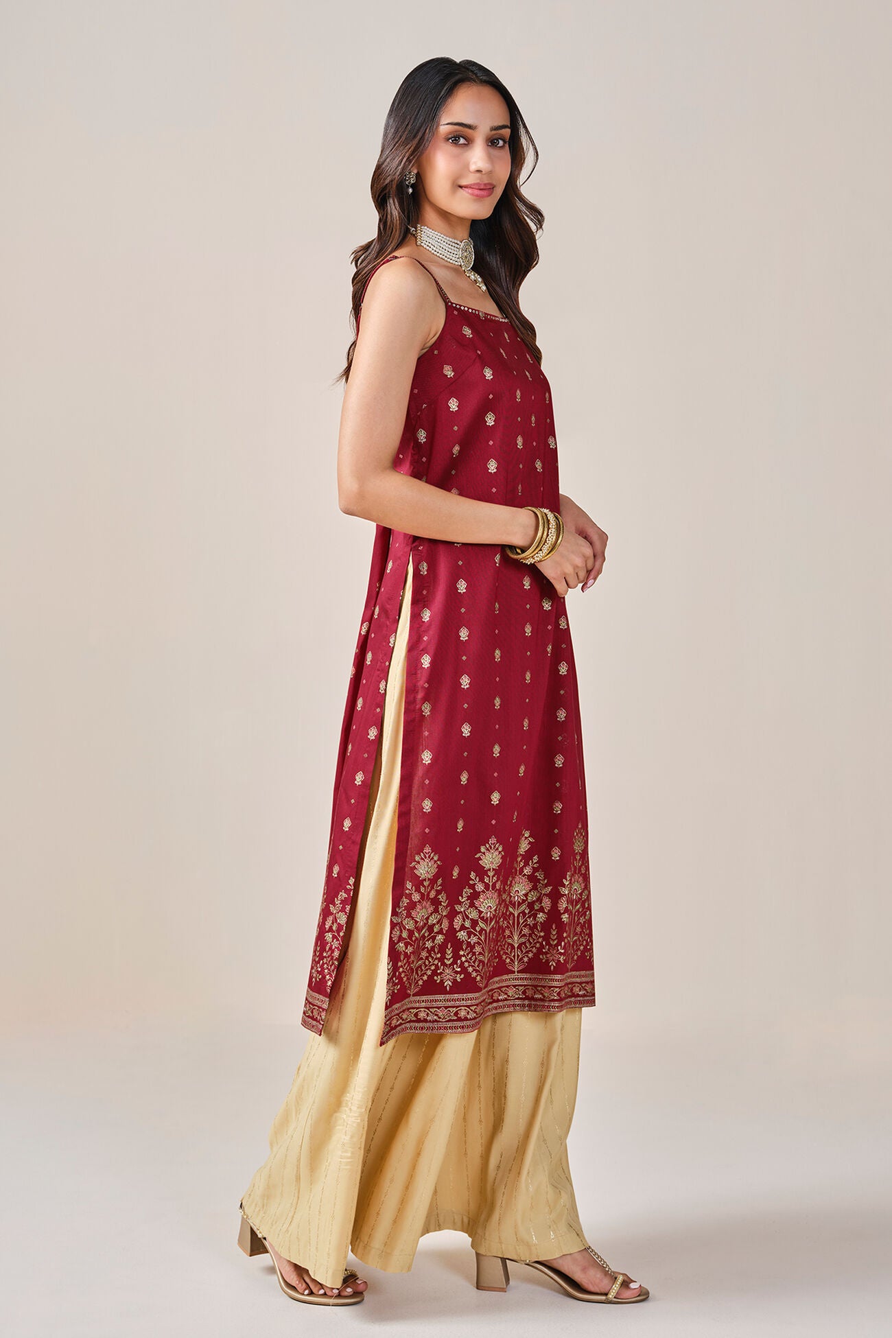 Woman wearing a red and beige traditional outfit on a plain background