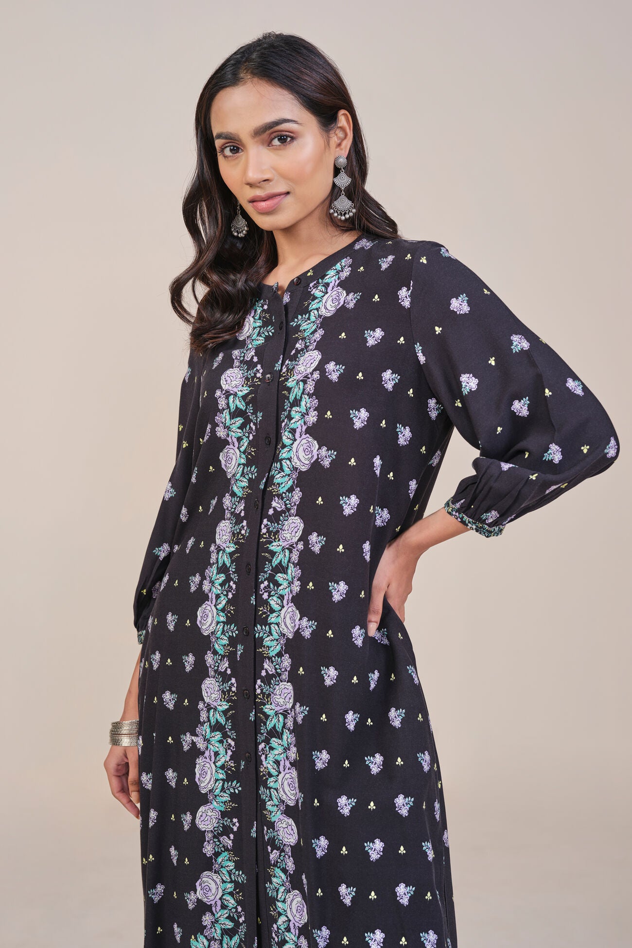 Woman wearing a black floral printed dress with a beige background