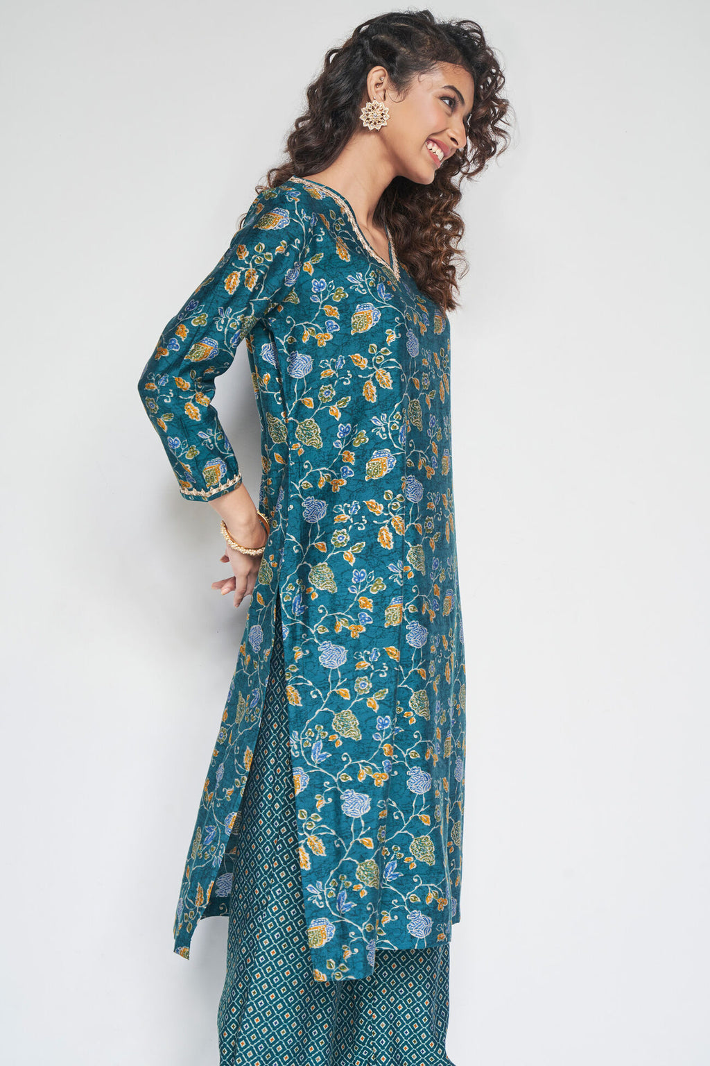 Woman wearing a teal floral dress against a white background