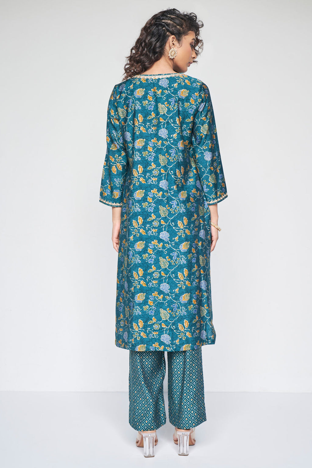 Woman wearing a teal floral kurta with matching pants on a white background