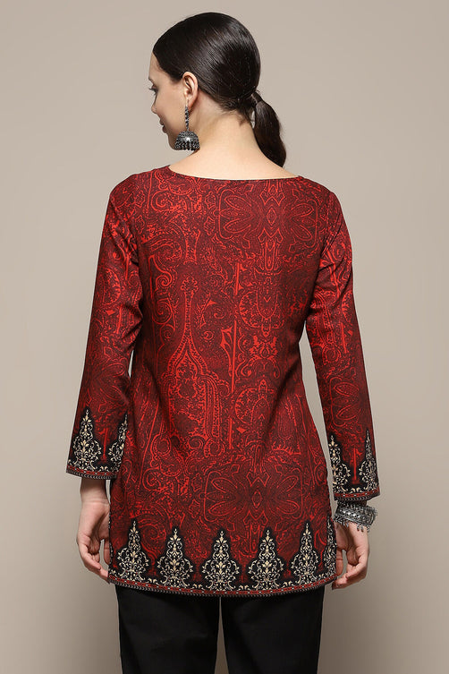 Red patterned top with black embroidery on a beige background