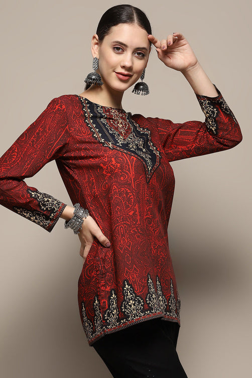 Woman wearing a red embroidered top with black details on a beige background