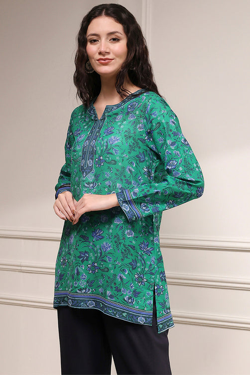 Woman wearing a green floral patterned top against a neutral background