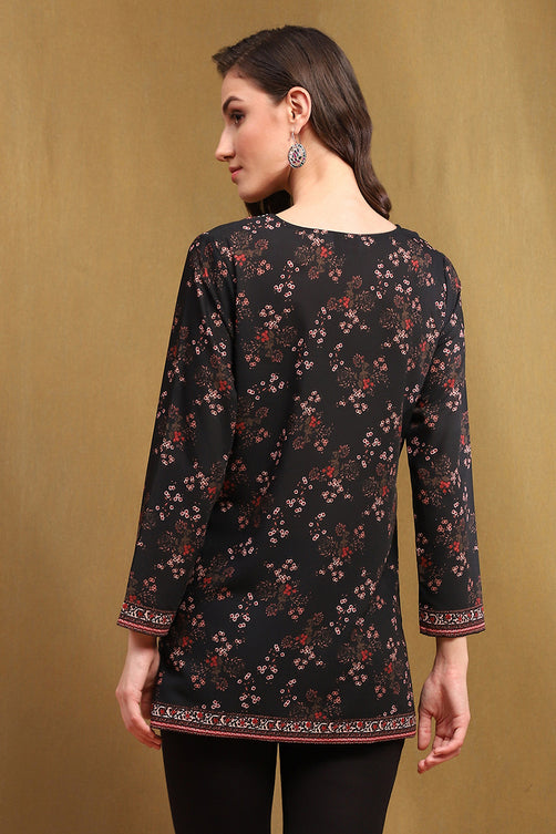 Woman wearing a black floral patterned top against a beige background