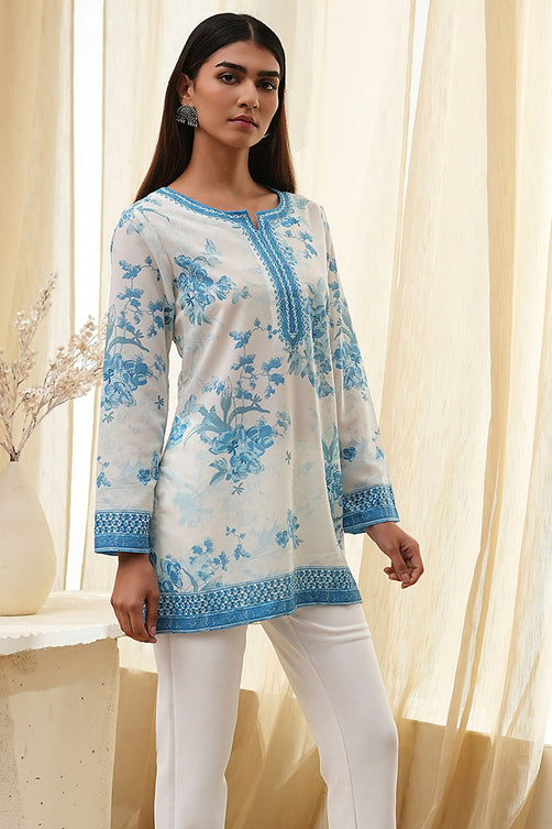 Woman wearing a light blue floral embroidered kurta with white pants against a neutral background