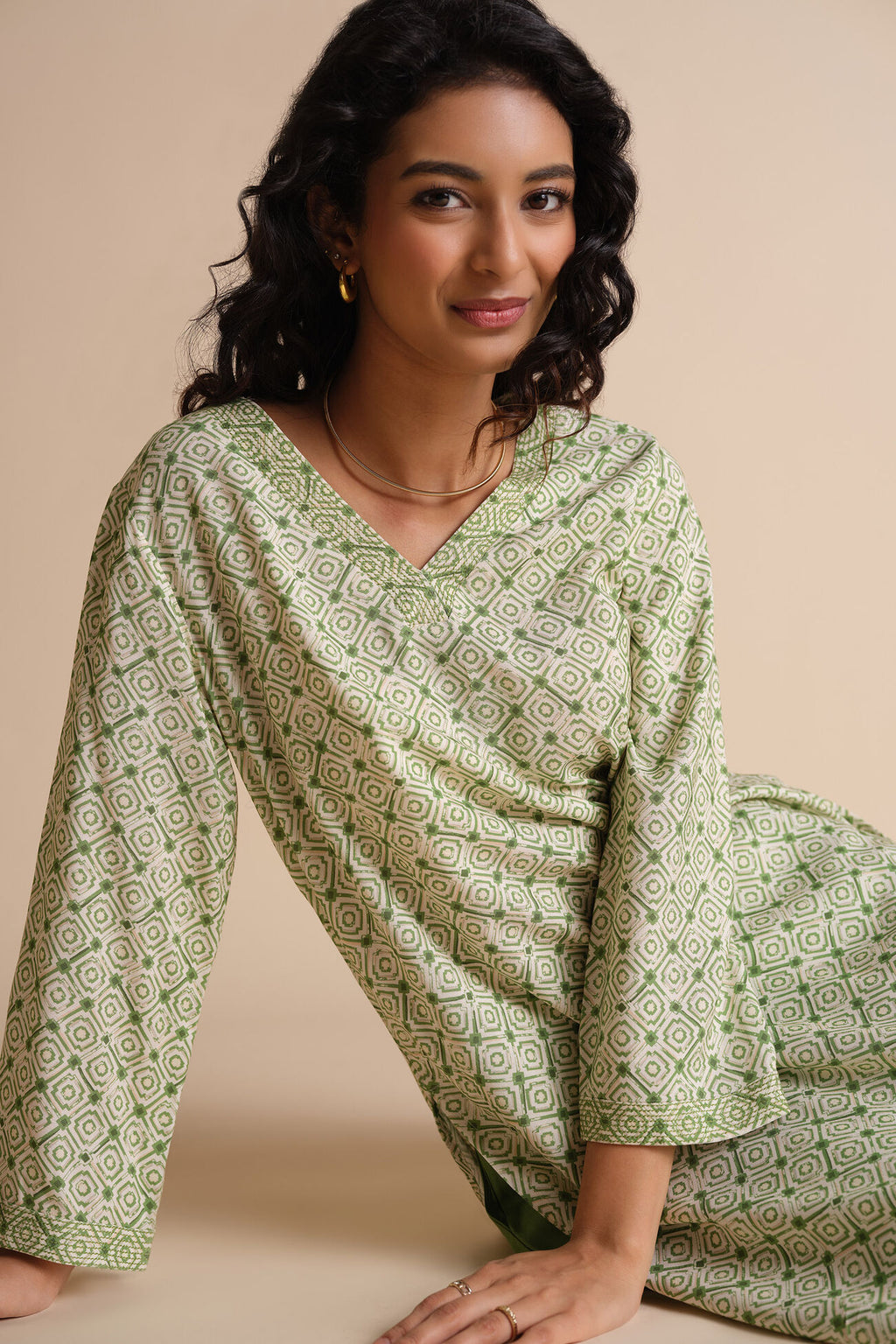 Woman wearing a green patterned outfit on a beige background