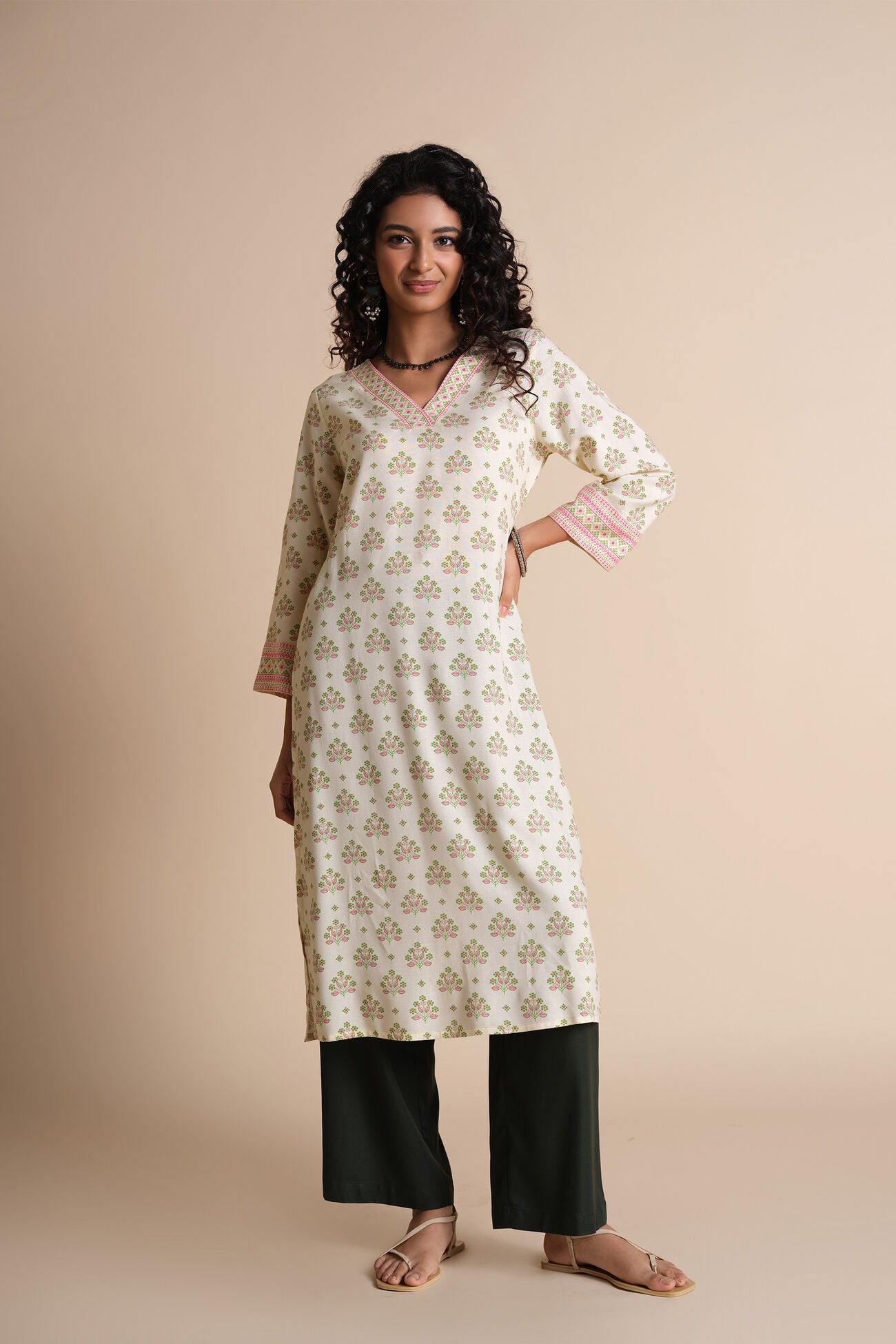 Woman wearing a floral kurta with black pants on a beige background