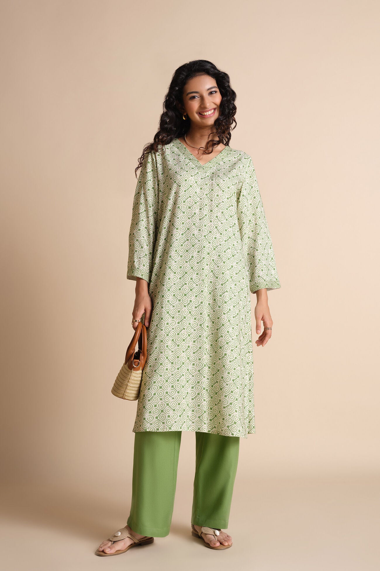 Woman wearing a green patterned kurta with green pants against a beige background