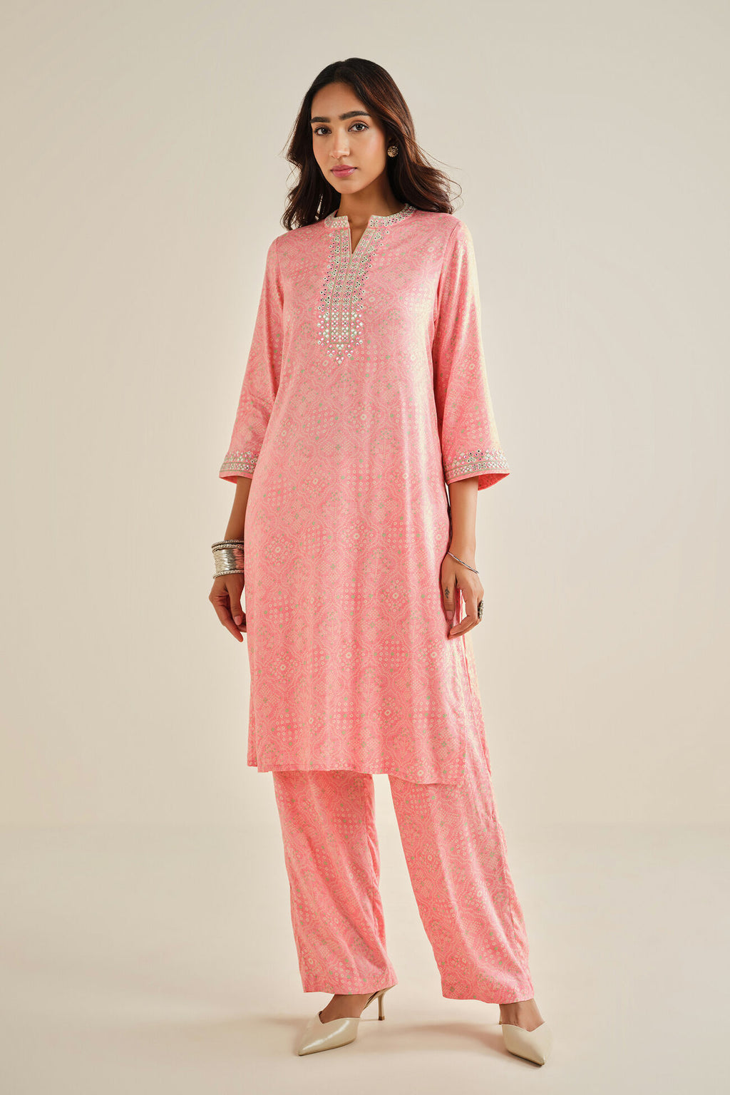 Woman wearing a pink traditional outfit with intricate designs on a beige background