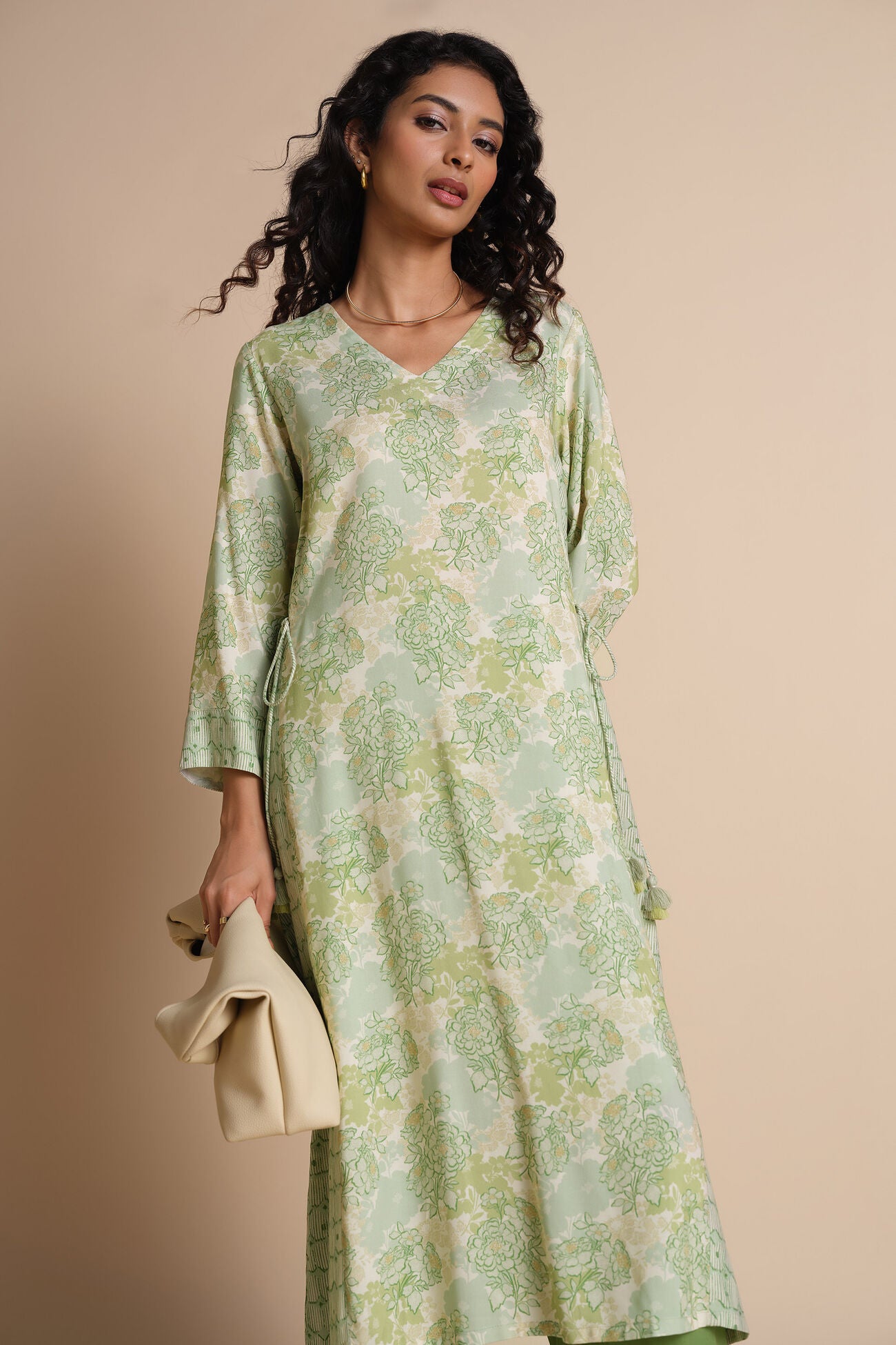 Woman wearing a green floral dress against a beige background