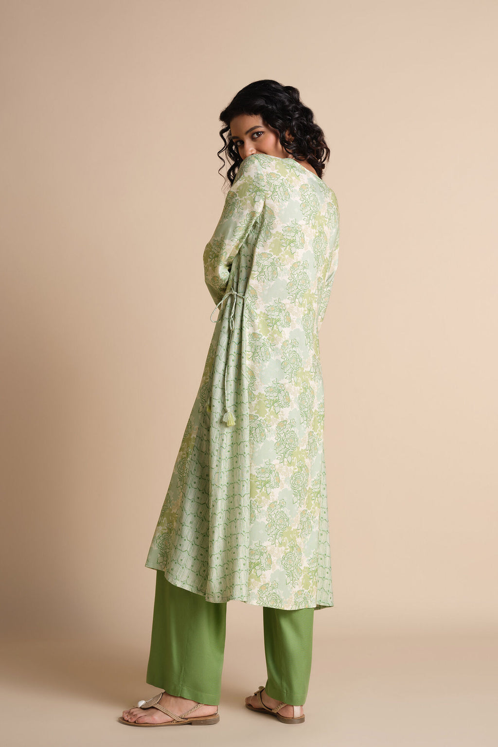 Woman wearing a green floral dress with a beige background