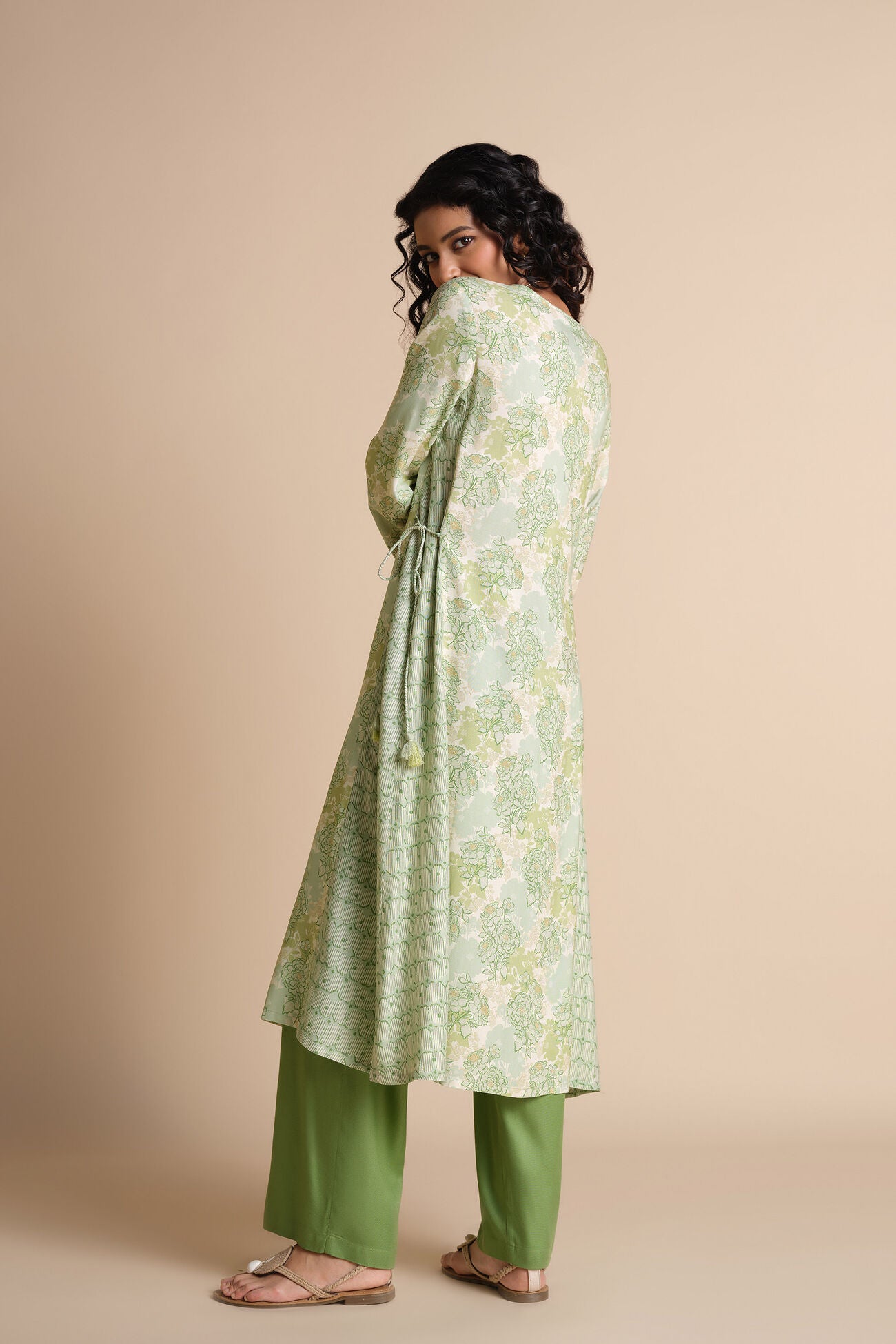 Woman wearing a green floral dress with a beige background